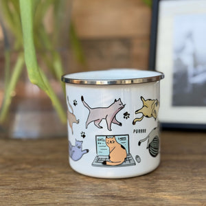 A colourful enamel mug with various cats and paw prints